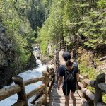 Femme de dos qui descend les escaliers à côté d'une chute d'eau