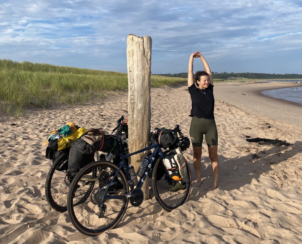 Une femme avec des vélos de bikepacking sur une plage